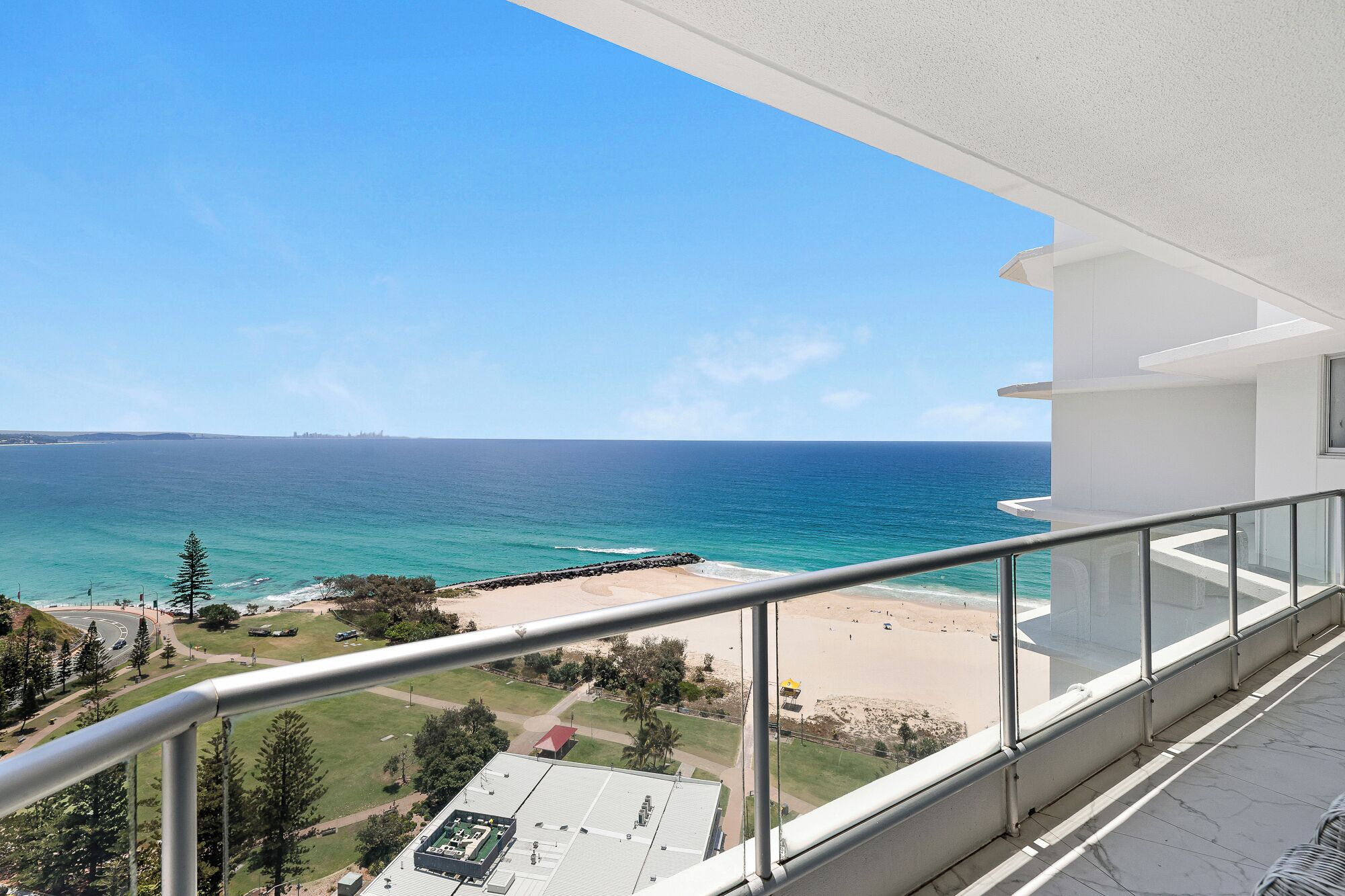 A balcony with a clear view of the ocean and beach.