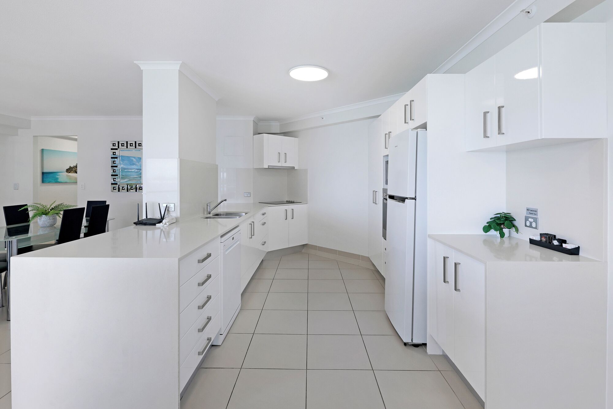 A modern kitchen with white cabinetry, a central island, and a dining area with chairs and a table.