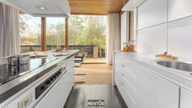 A modern kitchen with a central island, wooden ceiling, and large windows overlooking a deck. - ’t Zandhuis - vintage stay with garden in Ostend (Oostende)