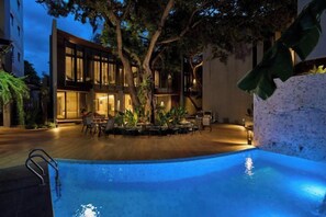 A swimming pool with a wooden deck, surrounded by outdoor furniture and a tree. - Red Door Hotel, Bangkok (Bangkok)