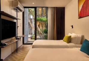 A hotel room with a TV, a bed with pillows, and a sliding glass door leading to a balcony with a view of a staircase and greenery. - Red Door Hotel, Bangkok (Bangkok)