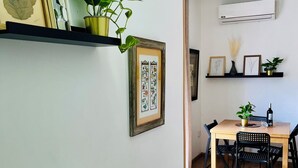 A dining area with a wooden table and chairs, a potted plant, and framed artwork on the wall. - Atico Duplex 4 Habitaciones 3 Terrazas Vista 360° (Barcelona)