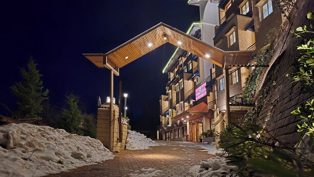 A hotel entrance with a covered walkway, snow on the ground, and a building with balconies and signage. - Shimla Golf Resorts (Shimla)
