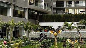 A modern building with multiple balconies and a well-maintained garden with various sculptures.