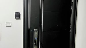 A modern elevator with a sleek black exterior and a control panel on the left side.