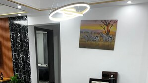 Un comedor con una mesa negra, sillas tapizadas en color beige y una lámpara colgante moderna.