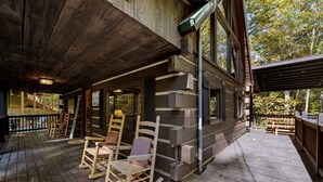 Una cabaña de madera con porche, mecedoras y terraza de madera.