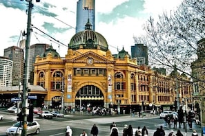A historic building with a large dome and arched windows, located at a busy intersection with modern skyscrapers in the background. - A Chic & Comfy 2BR Apt Near to Flemington Races (Melbourne)