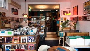 A bookstore with shelves of books and records, a staircase leading to another level, and a variety of framed pictures on the walls. - A Chic & Comfy 2BR Apt Near to Flemington Races (Melbourne)