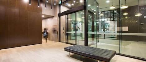 Un interior moderno con un banco, paredes de vidrio y luces colgantes.