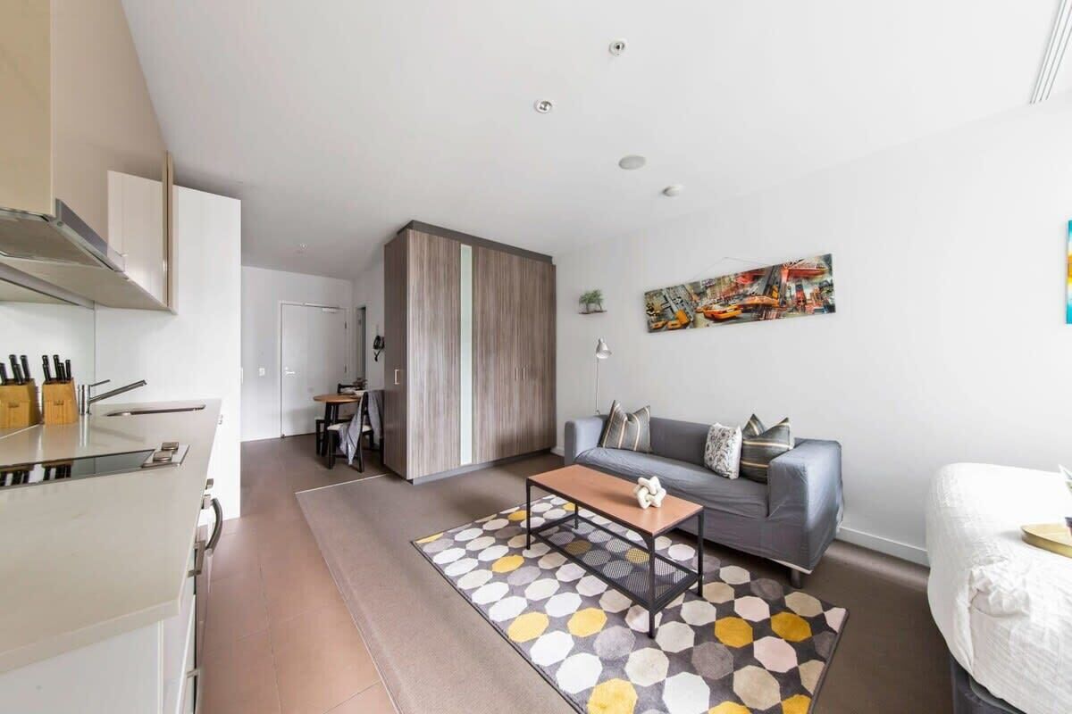 Um apartamento moderno com cozinha, sala de jantar, sofá e cama.