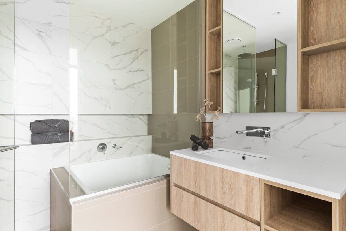 Une salle de bain moderne avec une grande baignoire, un lavabo avec un meuble-vasque en bois et un grand miroir.