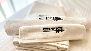 A neatly folded towel with 'CIVIC' embroidered on it, placed on a bed with a striped pattern.