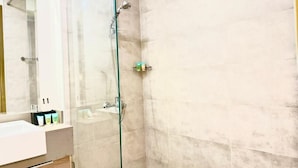 A modern bathroom with a glass shower enclosure, a white sink, and a mirror.