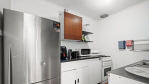 A compact kitchen with a stainless steel refrigerator, a microwave, a coffee maker, and a stove. - Beach house 2km CBD (South Melbourne)