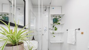 A modern bathroom with a glass-enclosed shower, white walls, and potted plants. - Beach house 2km CBD (South Melbourne)