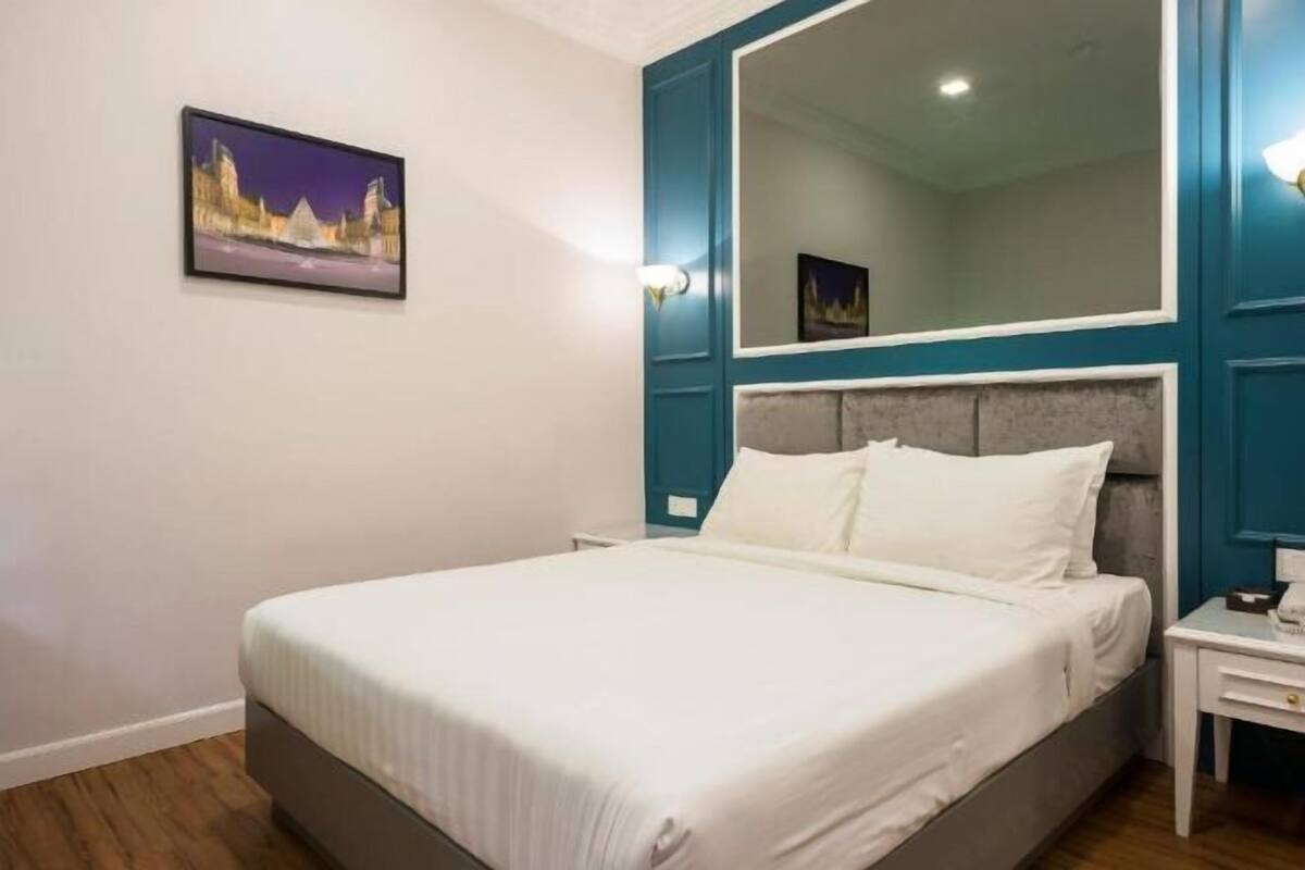 A bedroom with a bed, a nightstand, a mirror, and a wall-mounted picture.