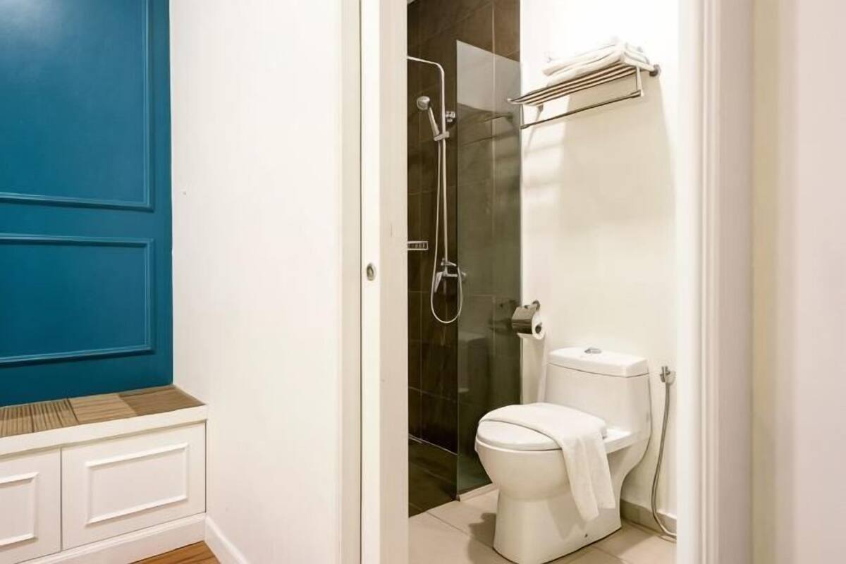 A bathroom with a white toilet, a glass shower enclosure, and a blue door.