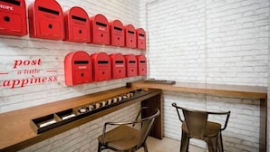 A room with a white brick wall, a wooden counter, and red mailboxes labeled with words like "TRUST" and "HOME". - H Boutique Hotel Sri Petaling (Kuala Lumpur)