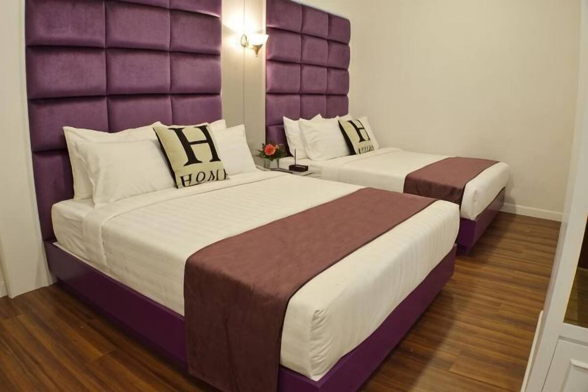 A double room with two beds, each with a headboard, a nightstand, and a mirror.