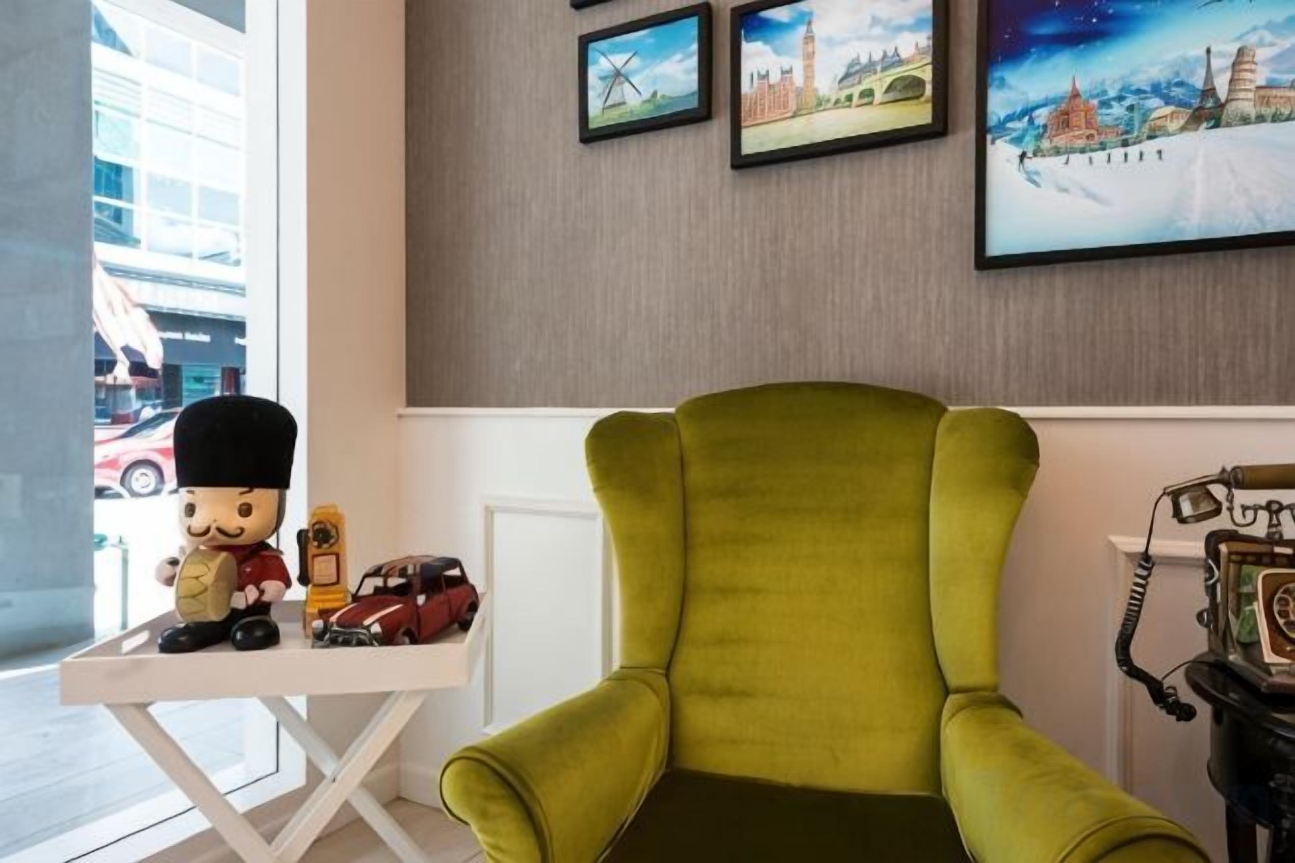 A room with a green armchair, a small table with figurines, and a vintage telephone.
