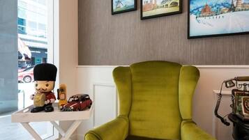 A room with a green armchair, a small table with figurines, and a vintage telephone.