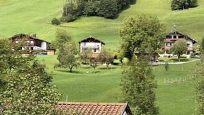 Un cadre rural avec des maisons entourées d’une végétation luxuriante et un paysage vallonné.