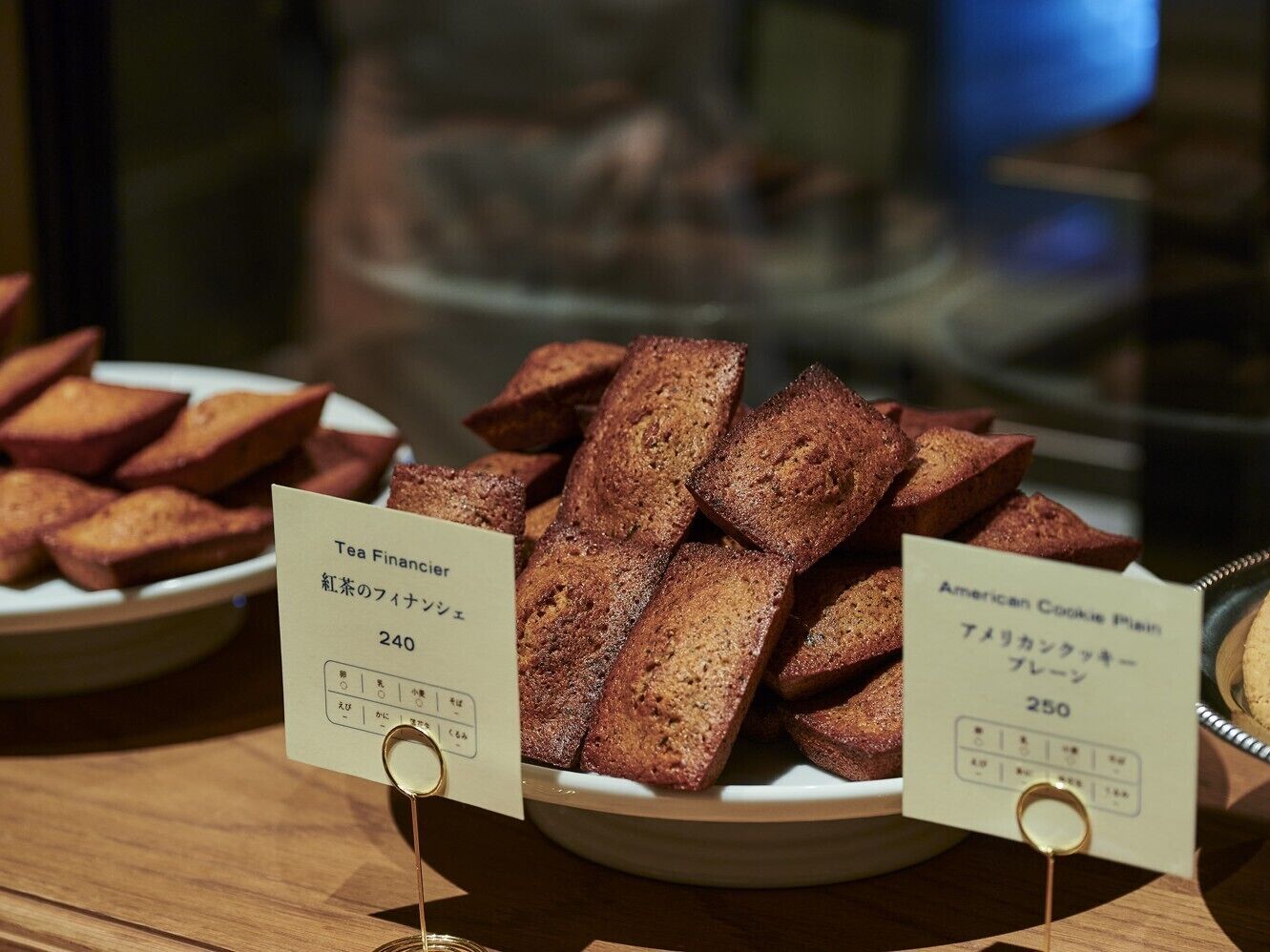 A display of bread with labels indicating 'Tea Financier' and 'American Cookie Plain.'