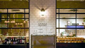 A bakery interior with a tiled wall, display cases, and a counter with bottles.