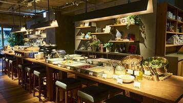 A long communal dining area with multiple barstools, a variety of food stations, and shelves with decorative items.