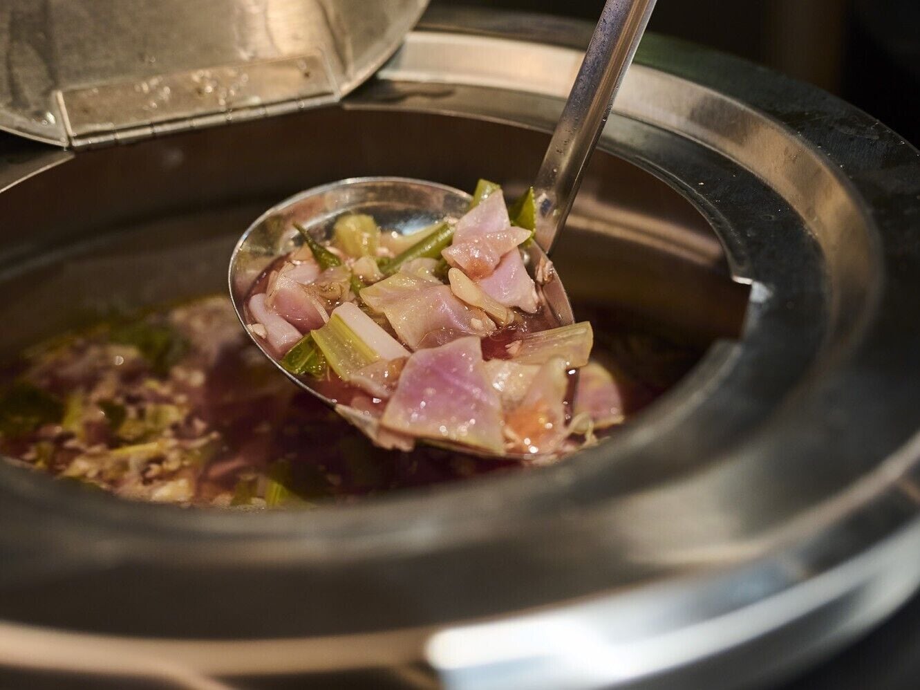 Alguien levanta una cucharada de comida de una cocedora lenta.