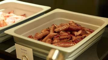 Un bufé con diversos platos, incluyendo salchichas y un plato con la etiqueta 'Salchicha'.