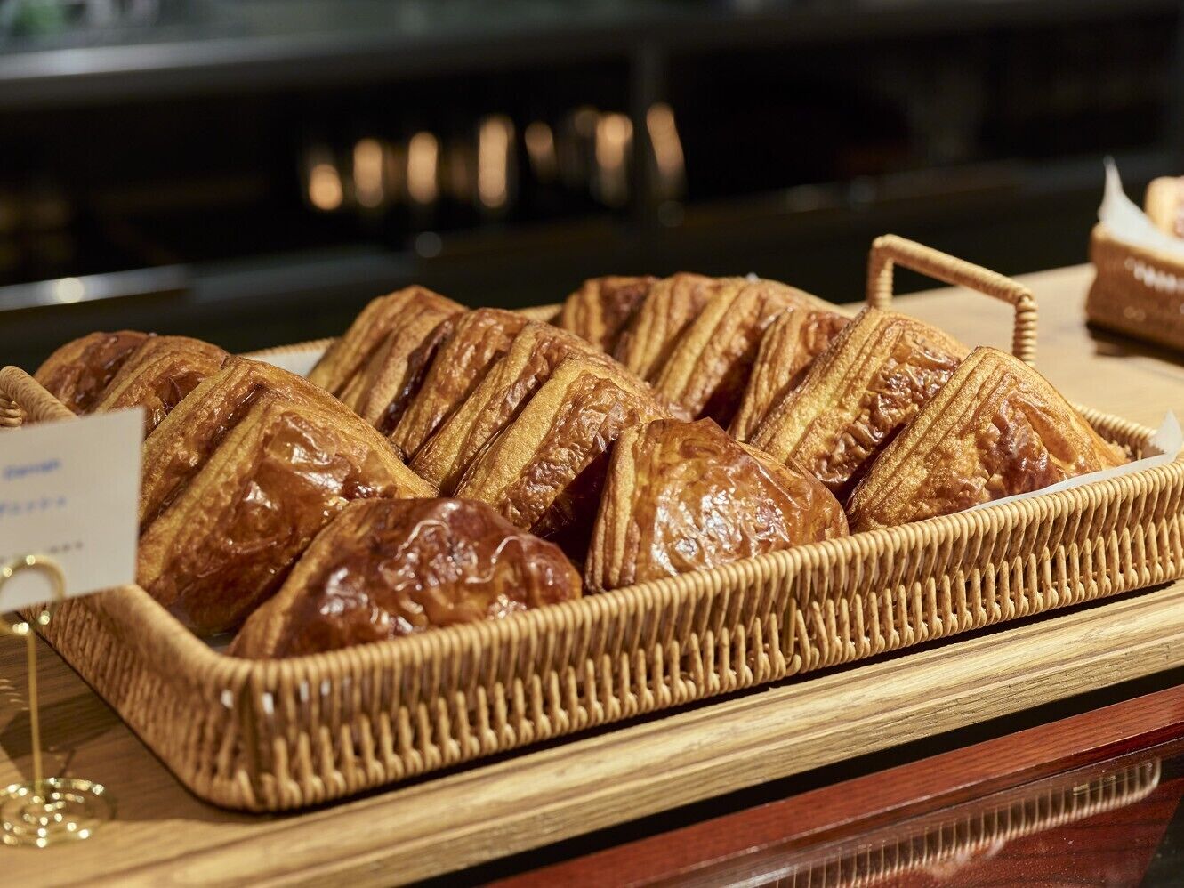 A wicker basket filled with glazed pastries on a wooden surface.