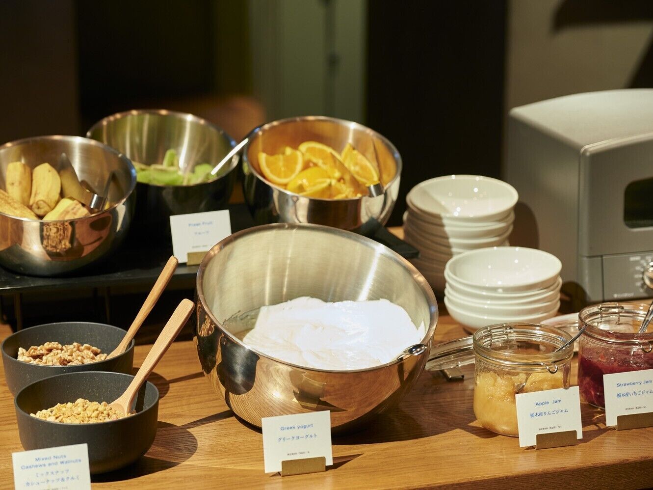 A buffet with various food items including Greek yogurt, apple jam, and orange slices.