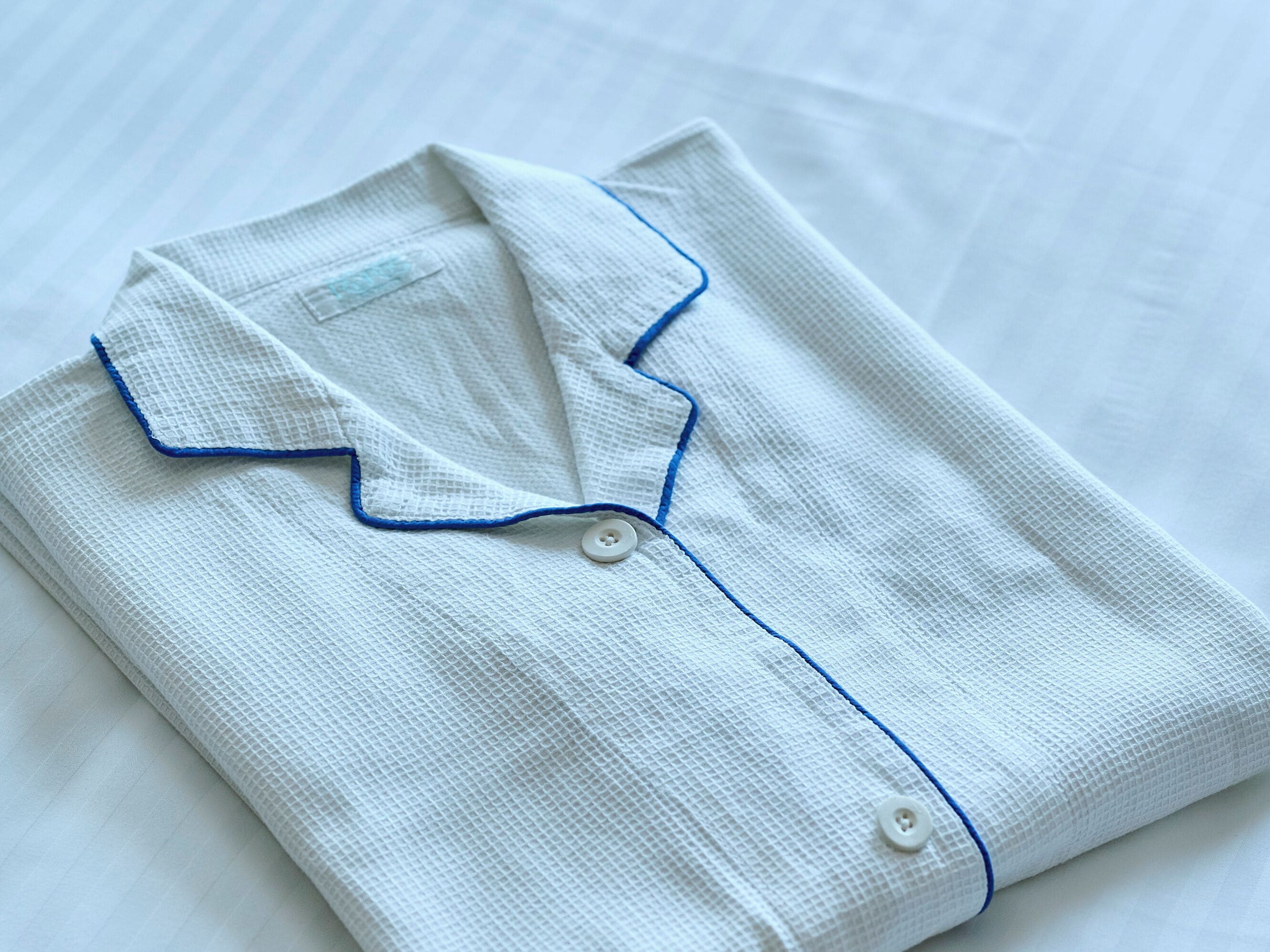 A neatly folded white shirt with blue trim and buttons.