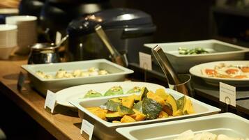 Un buffet proposant divers plats, notamment un plat composé de légumes coupés en tranches et un récipient contenant une substance blanche et crémeuse.