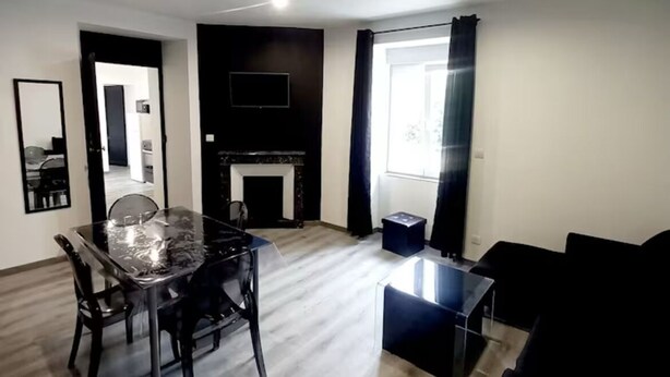 A modern living room with a glass dining table, black sofas, and a fireplace. - Les suites du jardin 4 (Chaumont)