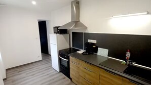 A modern kitchen with a stove, oven, and a stainless steel range hood. - Les suites du jardin 4 (Chaumont)
