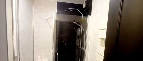 A bathroom with a toilet, a shower enclosure, and a sink.