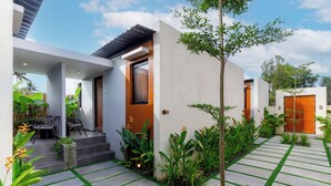 A modern house with a patio, outdoor seating, and lush greenery. - Andewi Cabin (Mengwi)