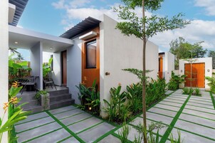 Una casa moderna con un patio, mobiliario exterior y exuberante vegetación.