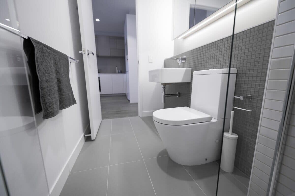 Une salle de bain moderne équipée de toilettes, d’un lavabo et d’une douche à parois de verre.