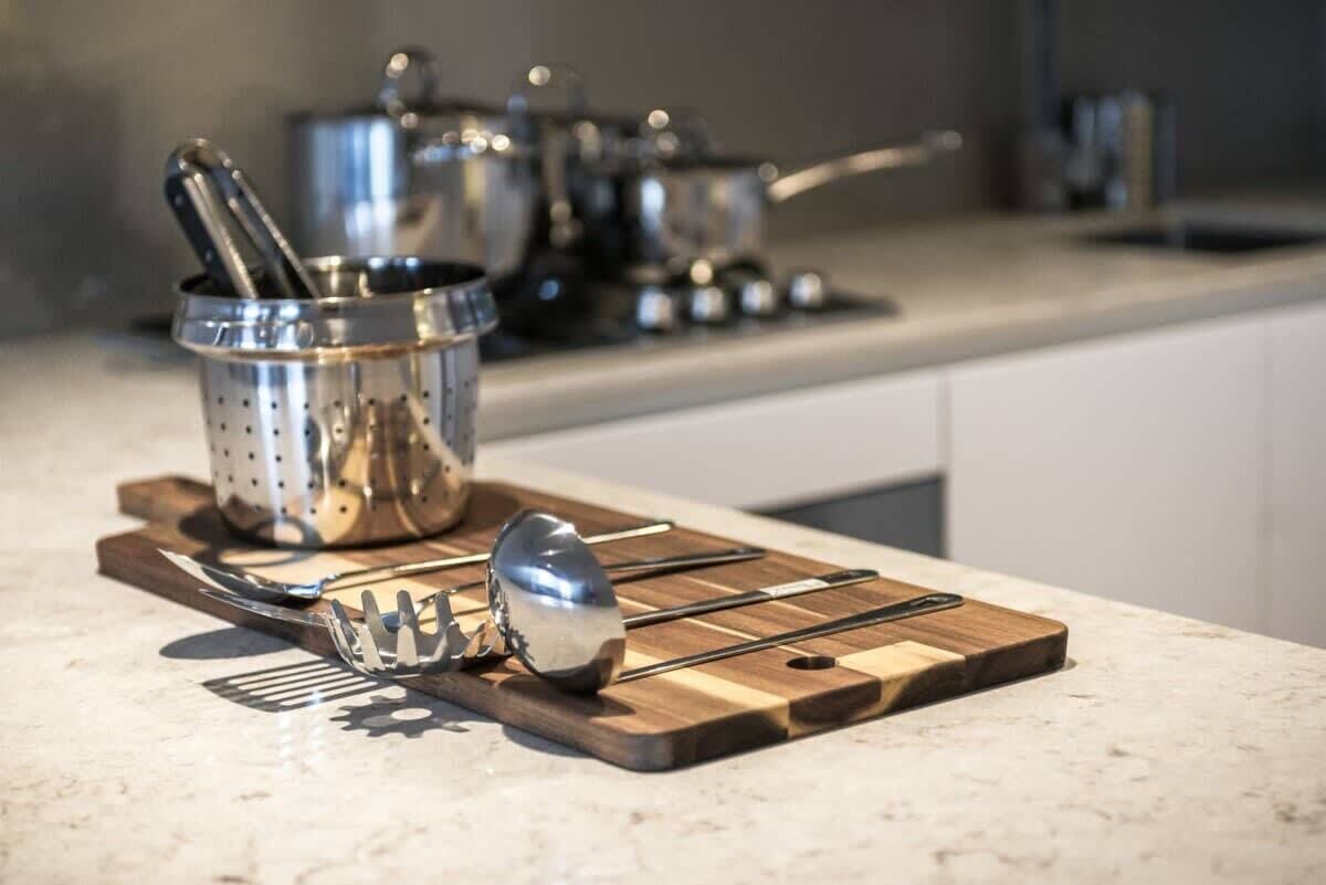 Een keukentrap met een houten snijplank, een vergiet en een lepel.