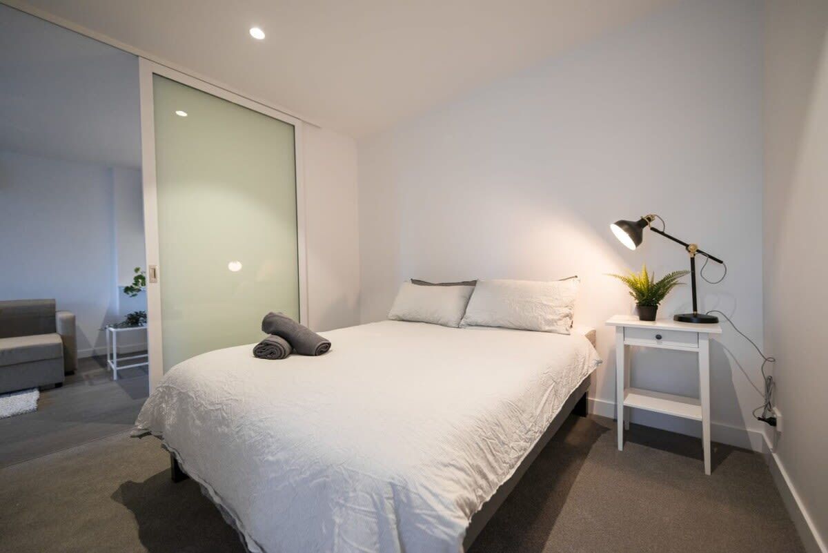 Une chambre moderne avec un grand lit, une table de chevet avec une lampe et une porte coulissante.