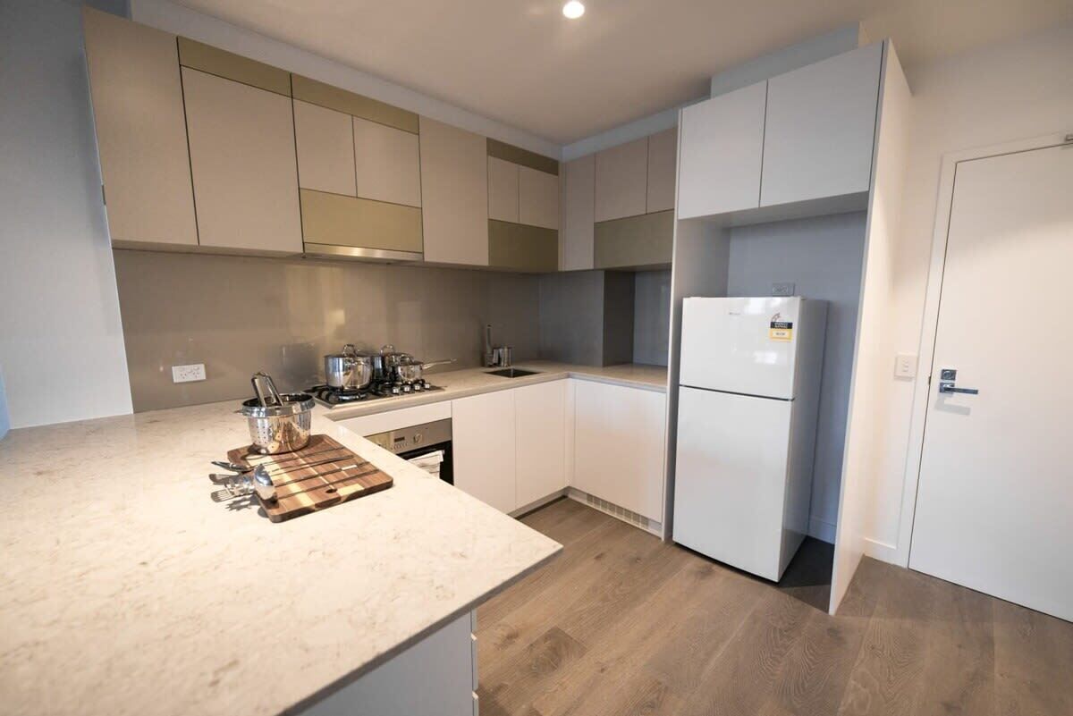 A modern kitchen with white cabinets, a stainless steel range, and a refrigerator.