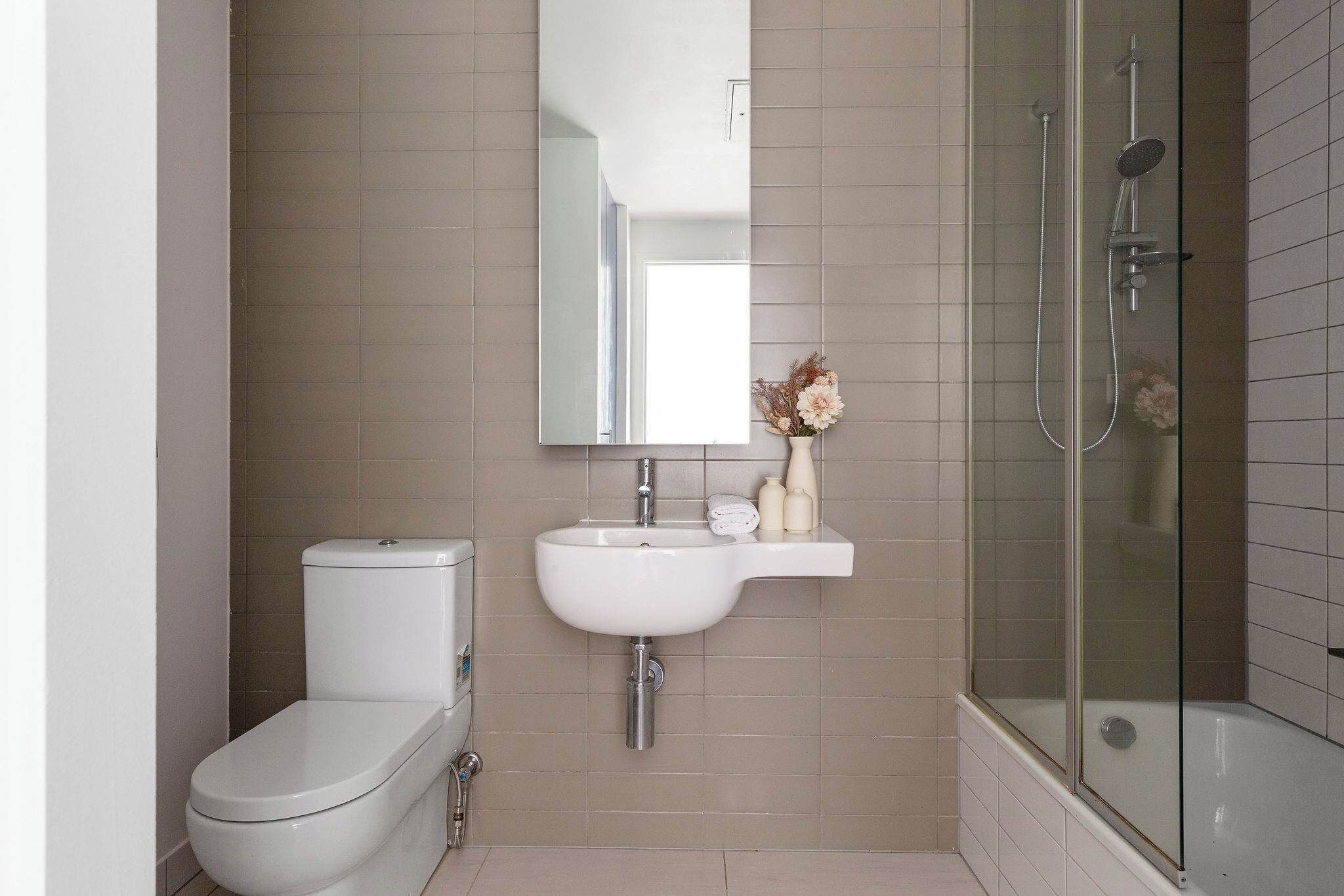 Ein Badezimmer mit Toilette, Waschbecken, Spiegel und Duschkabine.
