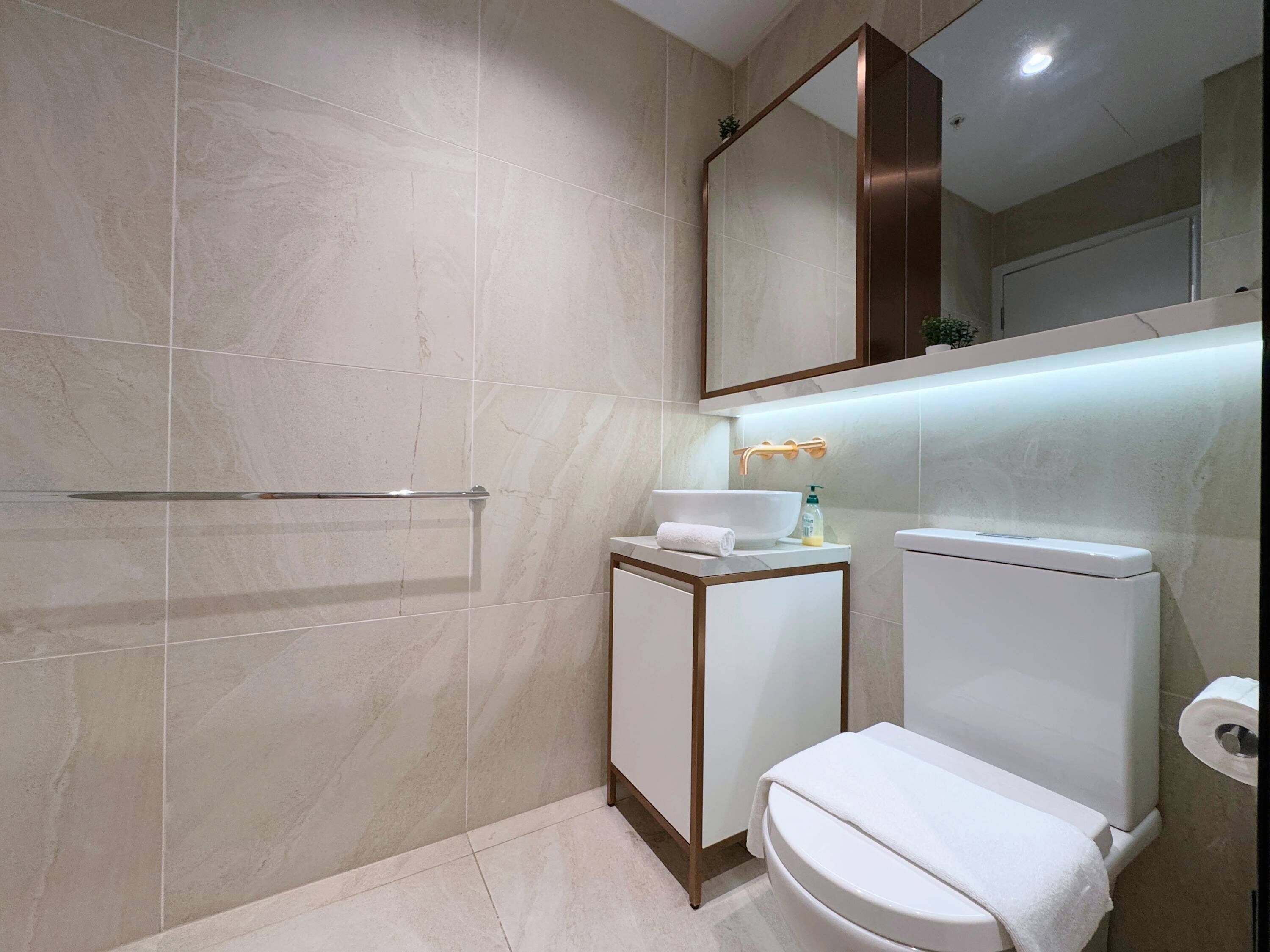 Un baño moderno con ducha a nivel, inodoro y lavabo.