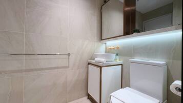 Un baño moderno con ducha a nivel, inodoro y lavabo.