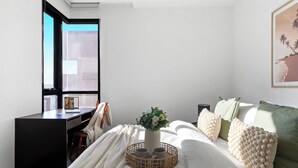 Ein Schlafzimmer mit einem Bett, einem Schreibtisch, einem Fenster und einem gerahmten Bild an der Wand.