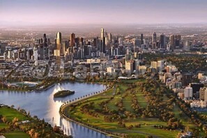 A cityscape with a prominent skyline, a large body of water, and surrounding green spaces.